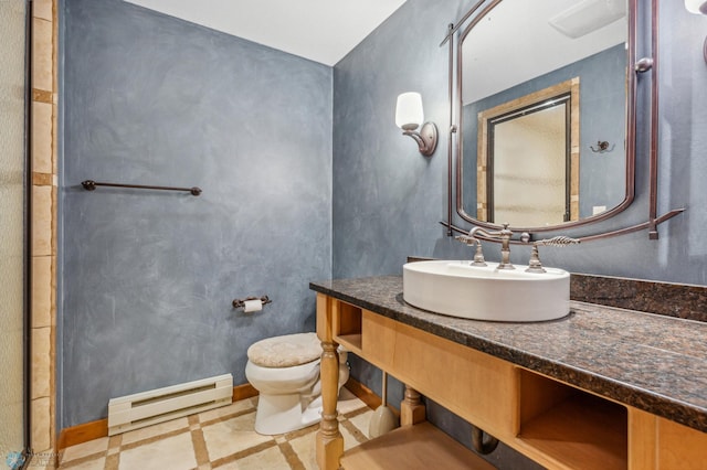 bathroom with toilet, vanity, a baseboard heating unit, and tile floors