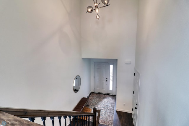 entryway with a towering ceiling, an inviting chandelier, and dark hardwood / wood-style flooring