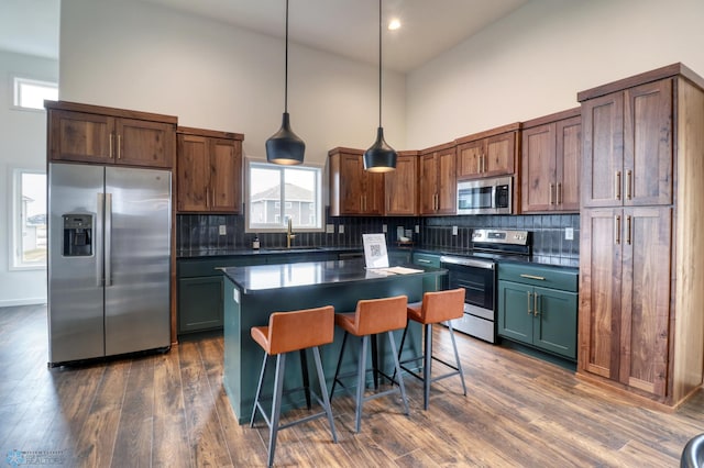 kitchen with dark hardwood / wood-style floors, tasteful backsplash, stainless steel appliances, a center island, and high vaulted ceiling