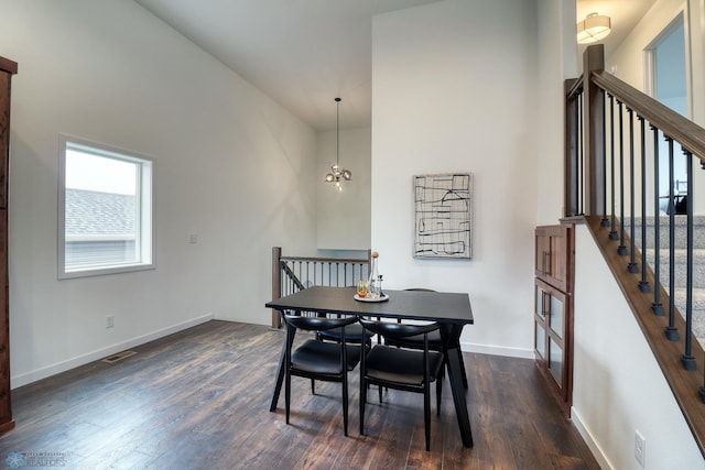 dining space featuring a towering ceiling, an inviting chandelier, and dark wood-type flooring