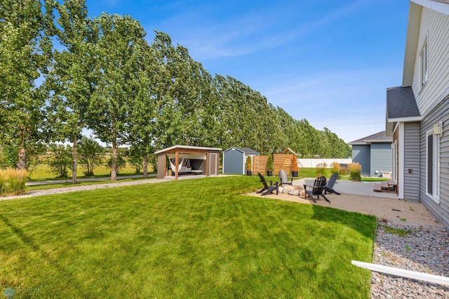 view of yard featuring a storage unit, an outdoor fire pit, and a patio area