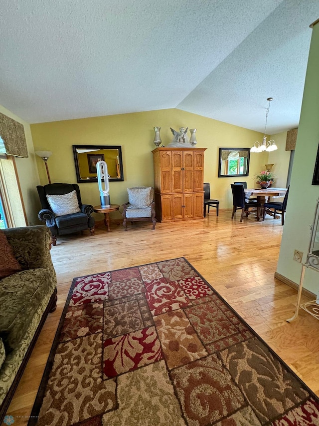 living room featuring lofted ceiling, plenty of natural light, a chandelier, and wood-type flooring