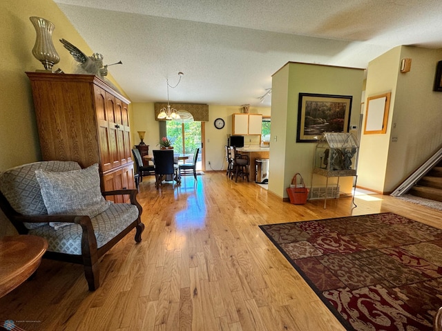 sitting room featuring a notable chandelier, a textured ceiling, light hardwood / wood-style flooring, and vaulted ceiling