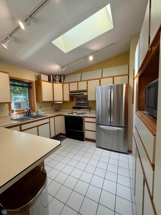 kitchen with appliances with stainless steel finishes, track lighting, vaulted ceiling with skylight, and a textured ceiling