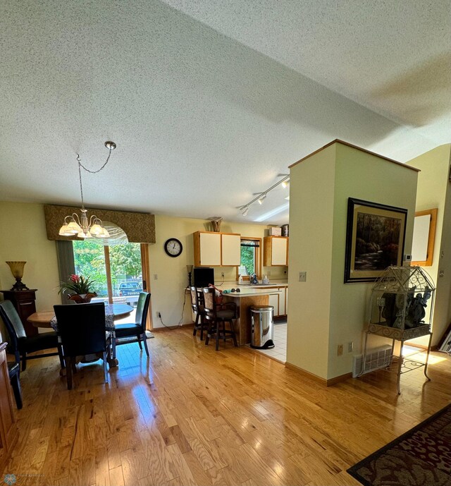 dining area with a textured ceiling, light hardwood / wood-style flooring, and a chandelier