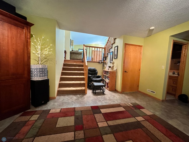 staircase with carpet floors and a textured ceiling