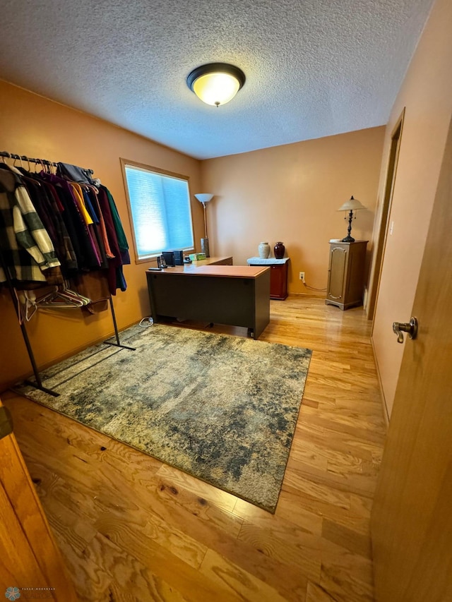 home office featuring light hardwood / wood-style floors and a textured ceiling