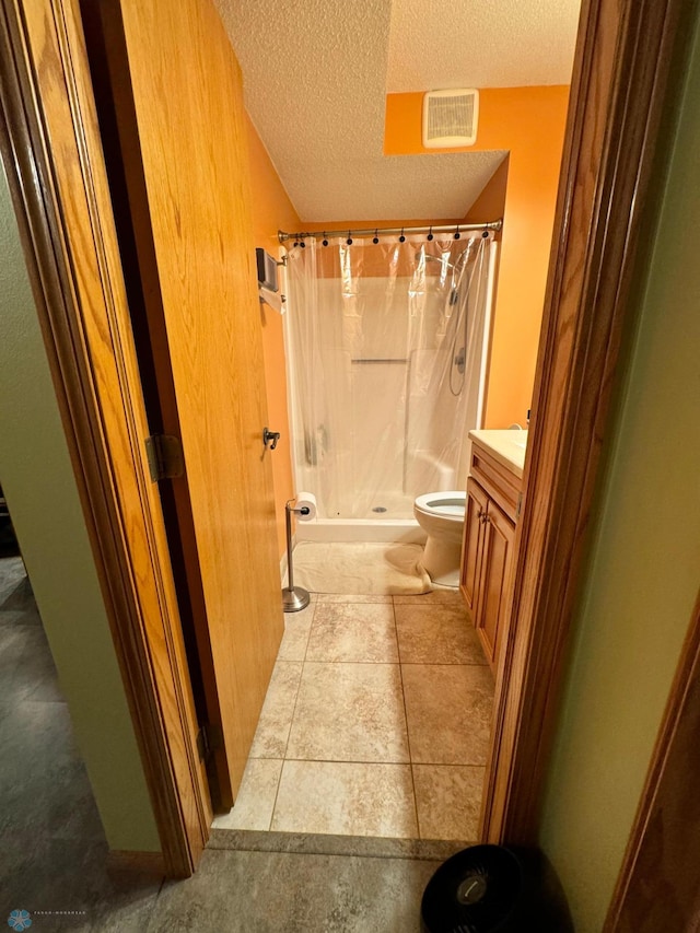 bathroom with vanity, a textured ceiling, tile patterned floors, a shower with curtain, and toilet