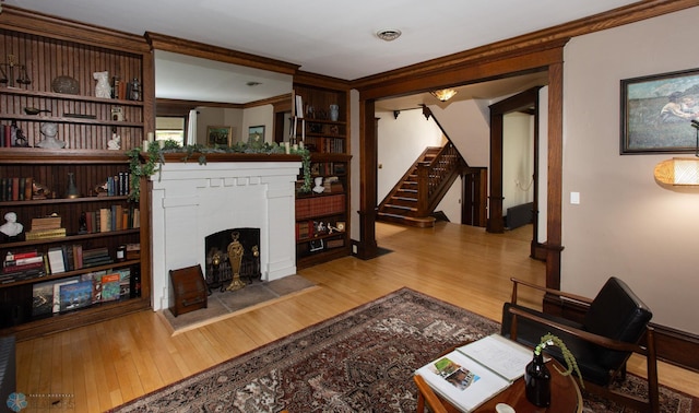 living room with light hardwood / wood-style floors, crown molding, and a brick fireplace