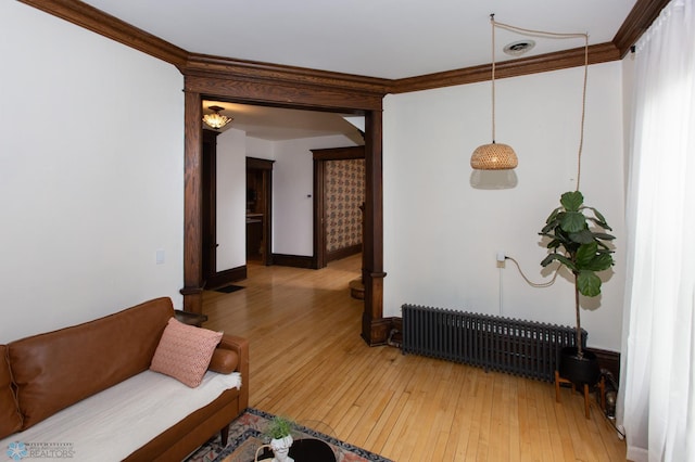 living room with ornamental molding, light hardwood / wood-style flooring, and radiator