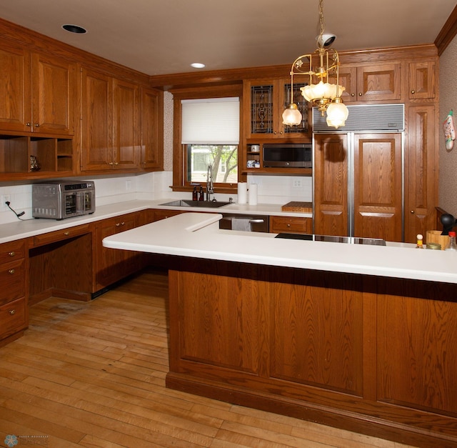 kitchen featuring stainless steel appliances, ornamental molding, sink, light wood-type flooring, and hanging light fixtures