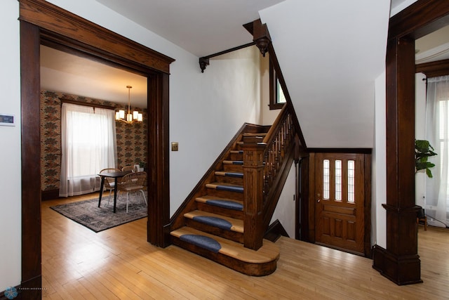 stairs with light wood-type flooring and a chandelier