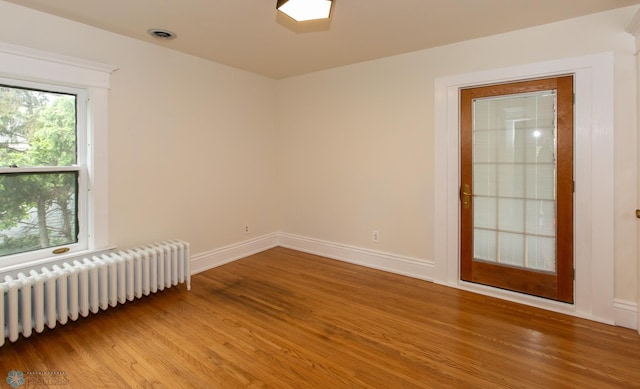 unfurnished room with radiator and wood-type flooring