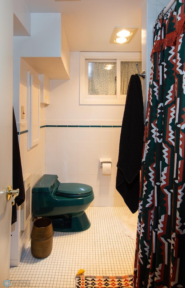 bathroom with toilet, tile patterned floors, and tile walls