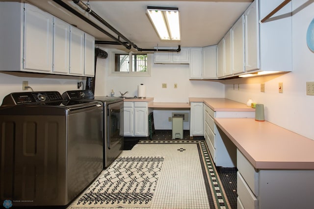 clothes washing area with light tile patterned flooring, washing machine and clothes dryer, and cabinets