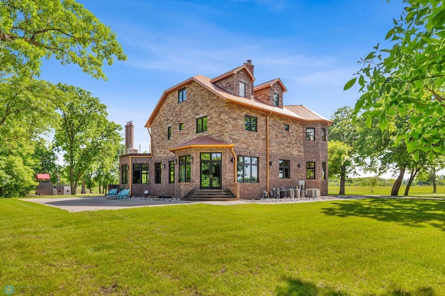 back of house with central AC and a lawn