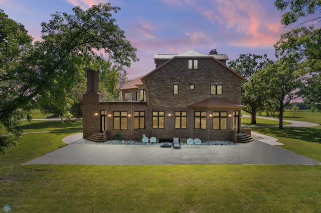 back house at dusk featuring a lawn