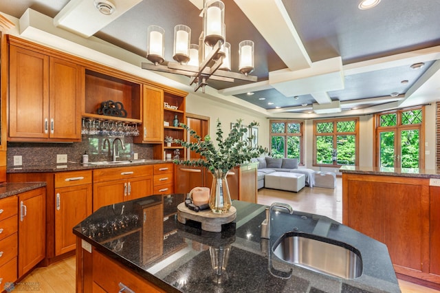 kitchen with dark stone countertops, tasteful backsplash, and a raised ceiling