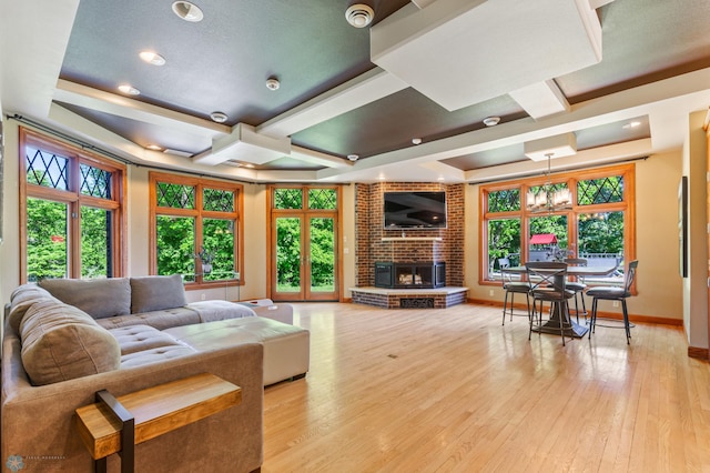 living room with brick wall, a brick fireplace, coffered ceiling, and light hardwood / wood-style flooring