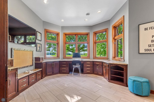 home office with built in desk, a wealth of natural light, and light tile flooring