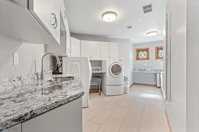 laundry area with washer / dryer, sink, light tile floors, and cabinets