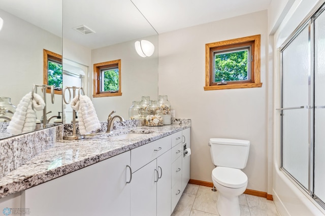 full bathroom with tile floors, bath / shower combo with glass door, large vanity, and toilet