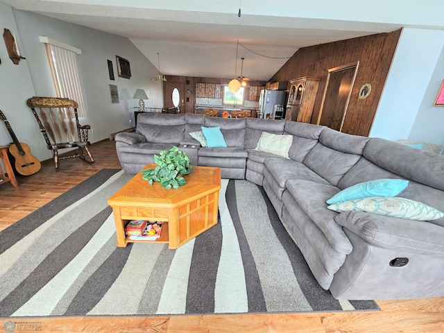 living room featuring wooden walls, hardwood / wood-style floors, and vaulted ceiling