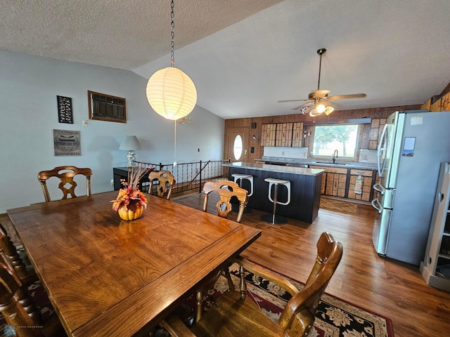 dining area featuring ceiling fan, a textured ceiling, hardwood / wood-style flooring, and vaulted ceiling