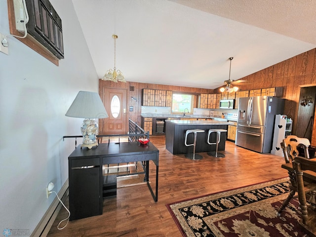 interior space with ceiling fan with notable chandelier, wood walls, dark hardwood / wood-style flooring, vaulted ceiling, and sink