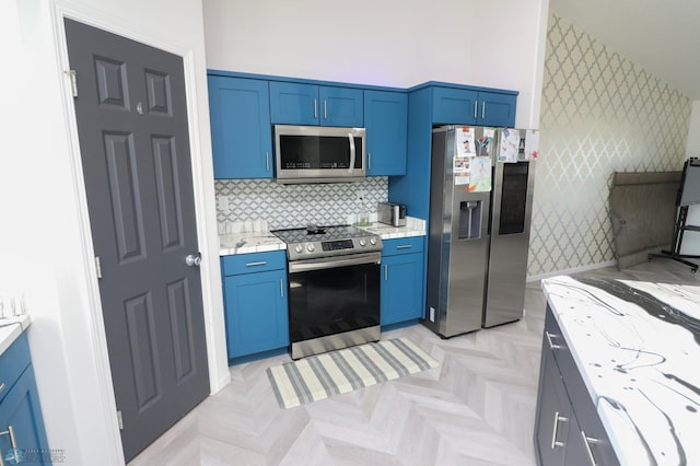 kitchen with light parquet floors, stainless steel appliances, blue cabinetry, light stone counters, and backsplash