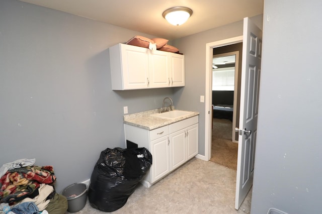 kitchen featuring light carpet, sink, and white cabinets