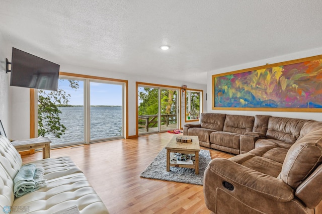 living room with a water view, light hardwood / wood-style floors, and a textured ceiling