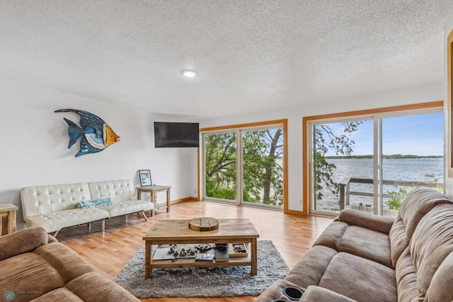 living room featuring a water view, light hardwood / wood-style floors, and a textured ceiling