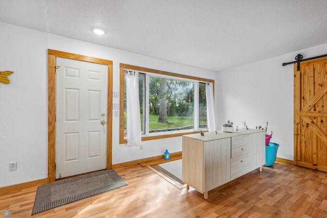 foyer with a barn door and light hardwood / wood-style floors