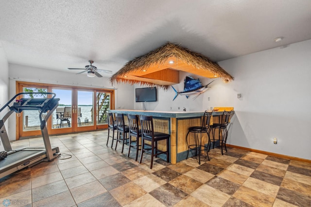 kitchen with a textured ceiling, tile floors, kitchen peninsula, ceiling fan, and a kitchen bar