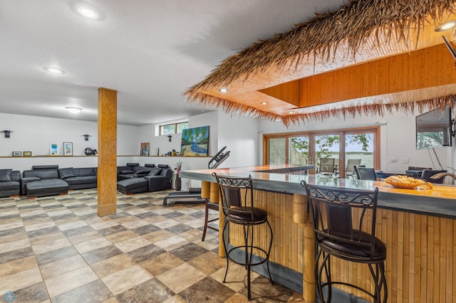 kitchen featuring a kitchen bar, a tray ceiling, and light tile floors