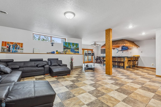 tiled living room with a baseboard heating unit, a textured ceiling, and ceiling fan