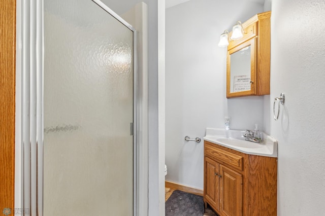 bathroom featuring a shower with door, vanity, and toilet