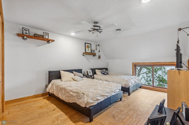 bedroom featuring ceiling fan, light hardwood / wood-style floors, a textured ceiling, and lofted ceiling