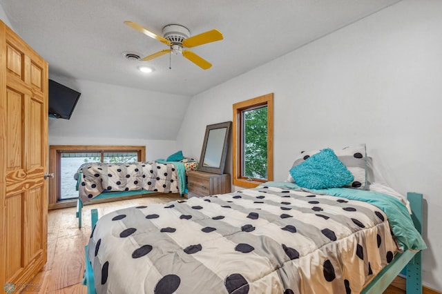 bedroom featuring ceiling fan, multiple windows, vaulted ceiling, and light hardwood / wood-style floors