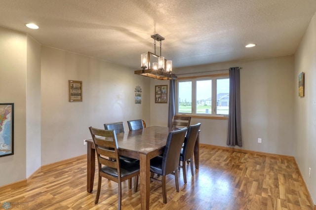 dining room with a chandelier, light hardwood / wood-style flooring, and a textured ceiling