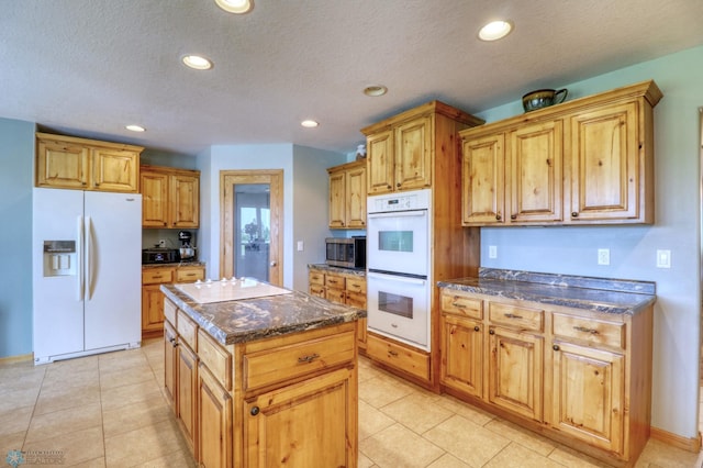 kitchen featuring a kitchen island, a textured ceiling, light tile flooring, and white appliances