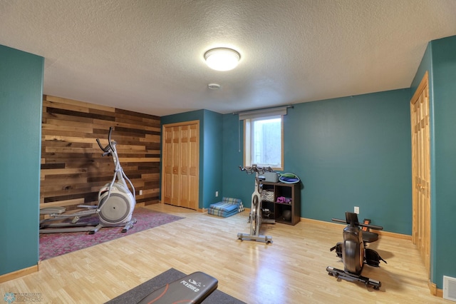 exercise area with hardwood / wood-style flooring, wood walls, and a textured ceiling