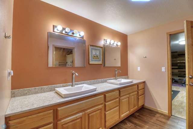 bathroom featuring a textured ceiling, double sink, oversized vanity, and wood-type flooring