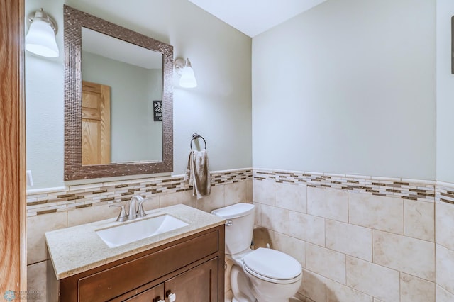 bathroom with tile walls, large vanity, and toilet