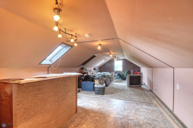 additional living space with vaulted ceiling with skylight, tile floors, and brick wall