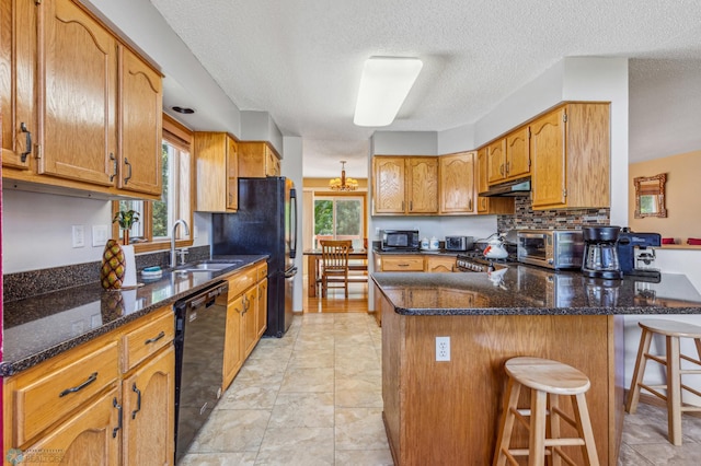 kitchen featuring a wealth of natural light, a kitchen bar, black appliances, and light tile floors