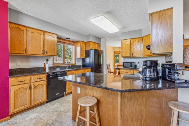 kitchen featuring a textured ceiling, black appliances, a breakfast bar, sink, and light tile floors