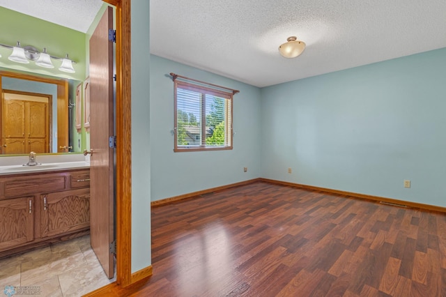 unfurnished bedroom with tile floors, sink, and a textured ceiling