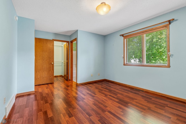 unfurnished bedroom featuring a textured ceiling, a closet, and hardwood / wood-style floors